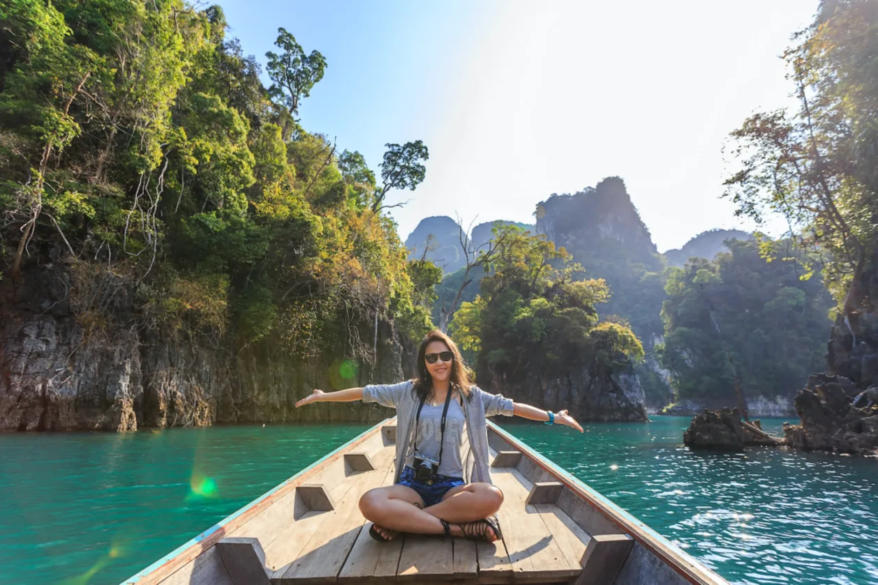 woman in wooden boat with arms open to maximize your wellness vacation